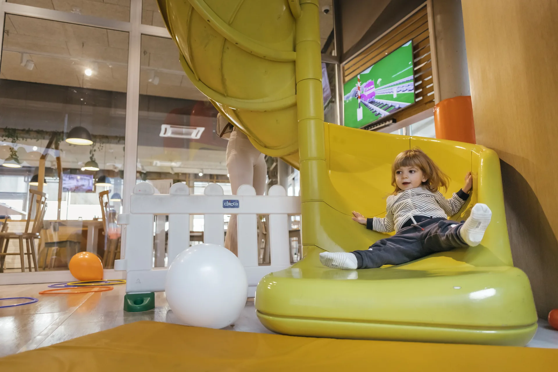 Un bambino si diverte sullo scivolo giallo nell’area kids Benvenuto