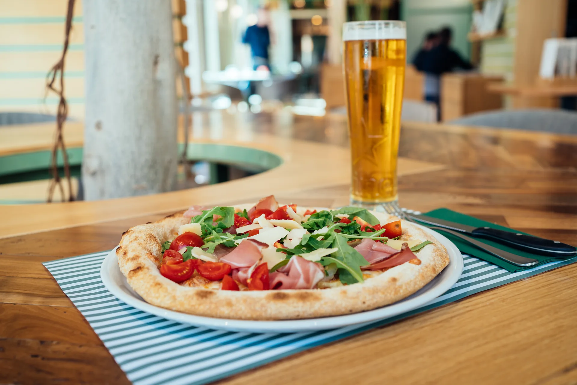 Pizza con prosciutto, rucola e pomodorini a tavola da Benvenuto