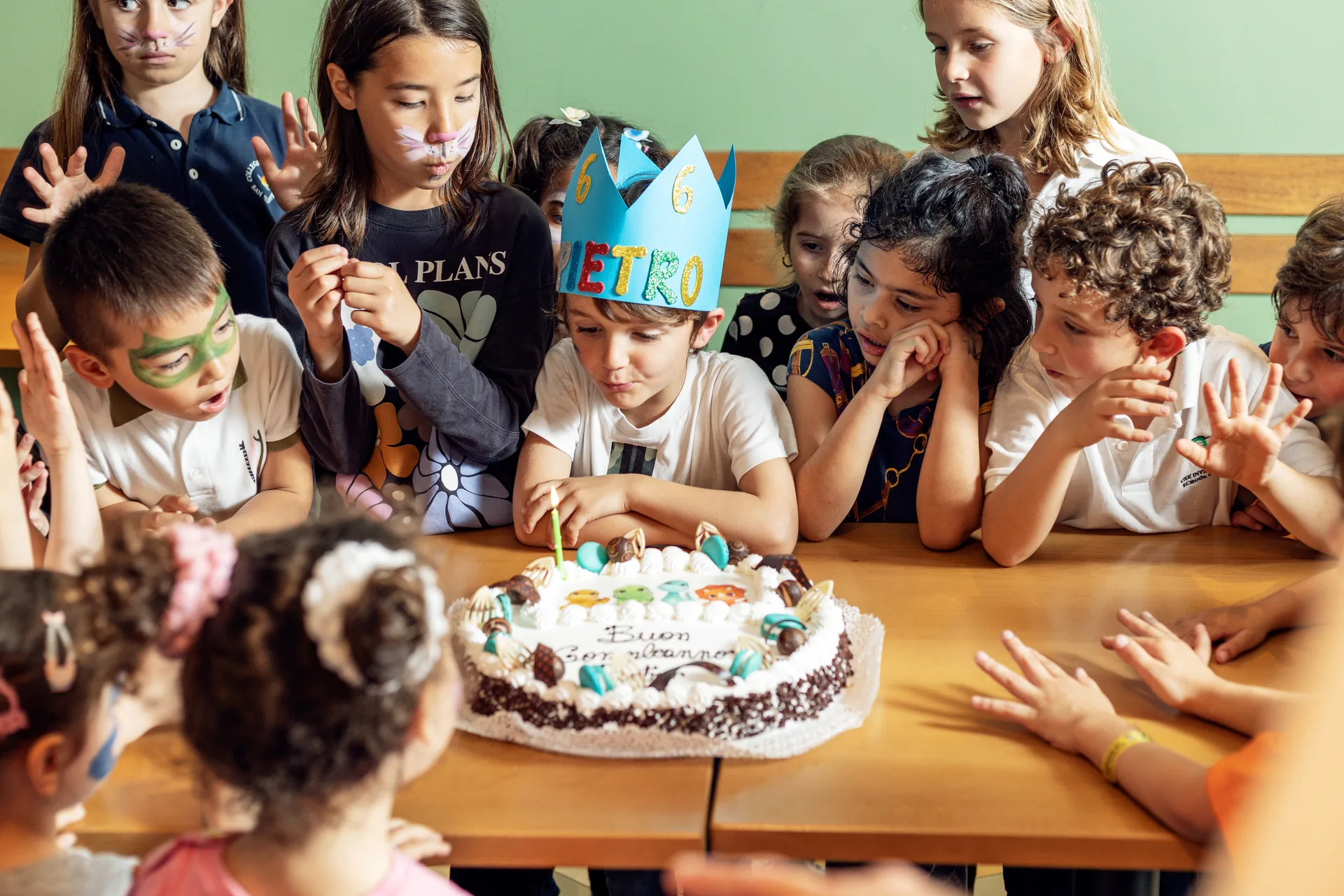 Bambini riuniti intorno alla torta durante una festa di compleanno Benvenuto